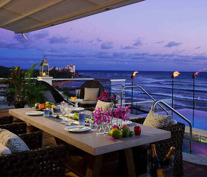 Rooftop dining setup at sunset with ocean view.